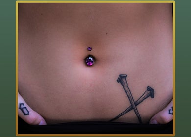 Close-up of a purple navel piercing at Gilded Touch Piercings, Glasgow, Scotland, GB, showcasing intricate tattoo art.