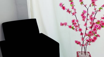 Sala de espera com cadeira preta e arranjo de flores rosa em Maiza Beauty - São Caetano do Sul, São Paulo, BR.