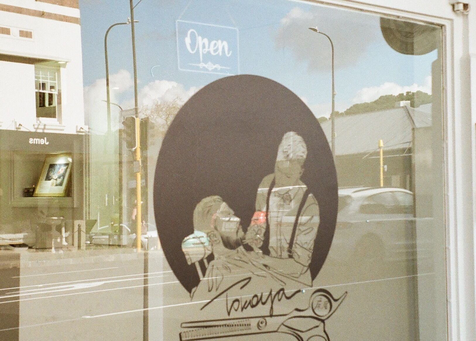 Tokoya Barber and Salon storefront in Auckland, NZ with reflection of street and buildings.