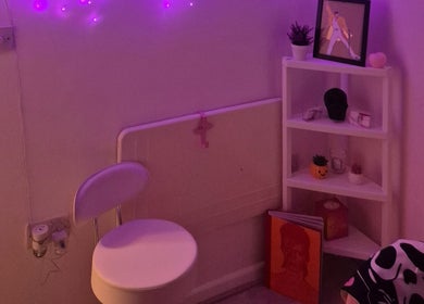 Purple-lit cozy corner at Roxystudio Nails, London with a chair and decorated shelves.