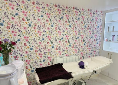 Elegant treatment room at Glow Beauty Salon, Maidenhead, England, GB with floral wallpaper and massage bed.