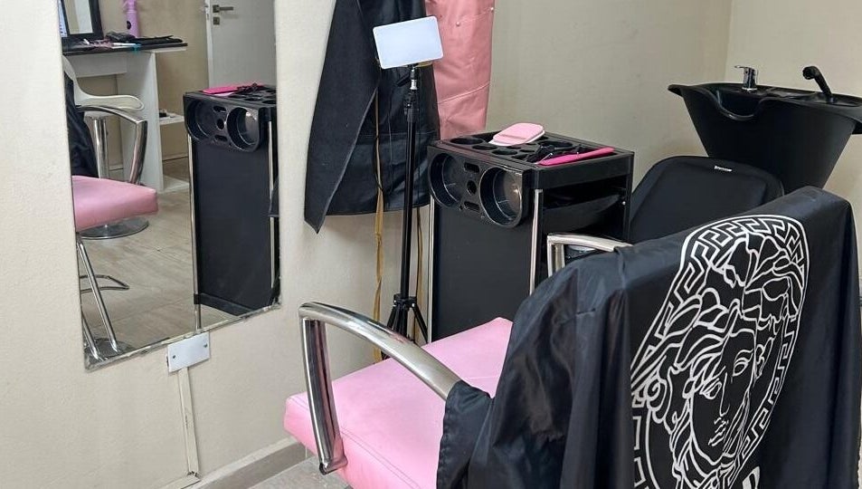Silla rosa elegante en El Salon De Pelo, Córdoba, AR con tocador y fregadero moderno.