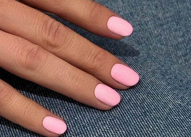 Pink manicured nails on denim at Adela nail studio, Thessaloniki, GR, offering chic nail art.