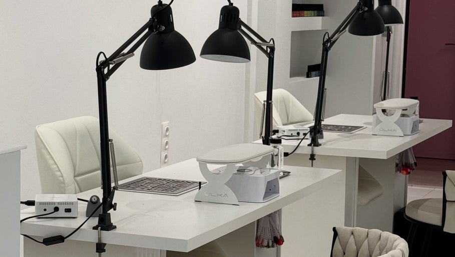 Modern nail stations at Adela nail studio in Thessaloniki, GR, featuring sleek white tables and elegant chairs.