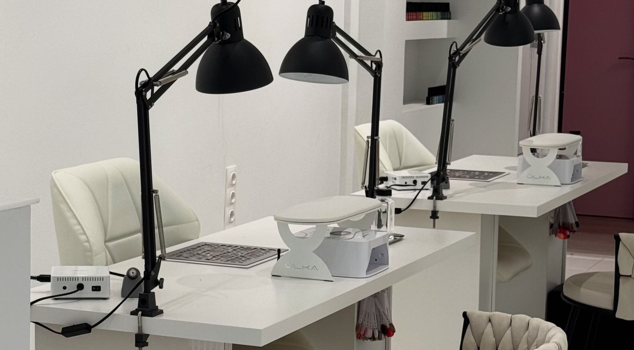 Modern nail stations at Adela nail studio in Thessaloniki, GR, featuring sleek white tables and elegant chairs.