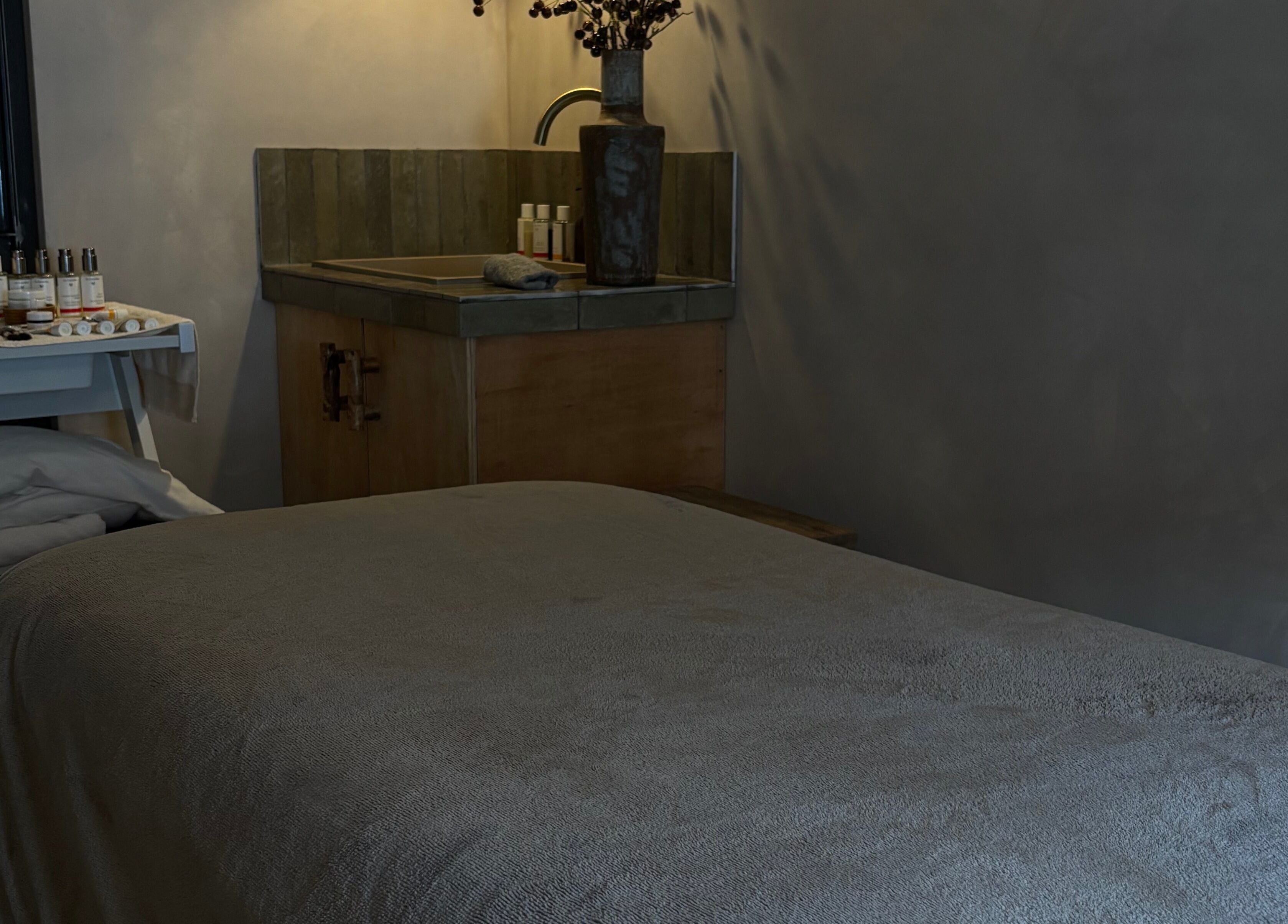 Relaxing treatment room at Elaine Sadler Skin Health, Warwick, England, GB, featuring cozy bed and skincare products.
