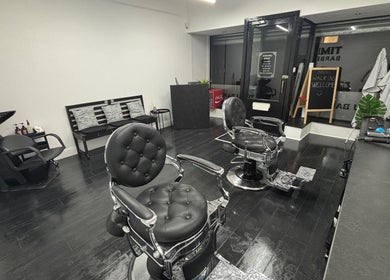 Modern interior of TIMI J BARBERS in Paisley, Scotland, GB, featuring stylish black chairs and sleek decor.