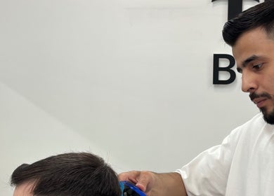 Barber at TIMI J BARBERS in Paisley, Scotland, GB, expertly cutting a client's hair.