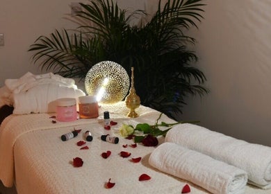 A calming massage table setup at Relive Spa, Al Rayyan, Doha Municipality, QA, with candles and rose petals.
