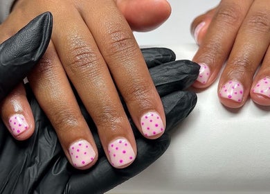 Stylish pink polka dot manicure at Nailsbybry, Ampthill, England, GB enhances hand beauty.