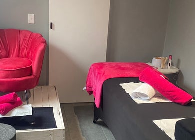 Relaxing treatment room at The Beauty Pond, Cape Town, Western Cape, ZA with vibrant pink chair and towels.