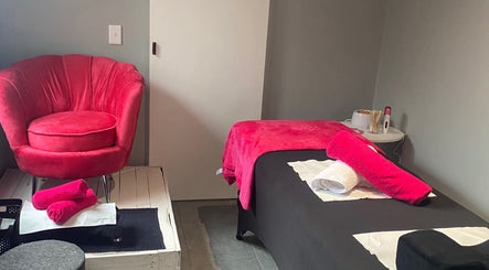 Relaxing treatment room at The Beauty Pond, Cape Town, Western Cape, ZA with vibrant pink chair and towels.