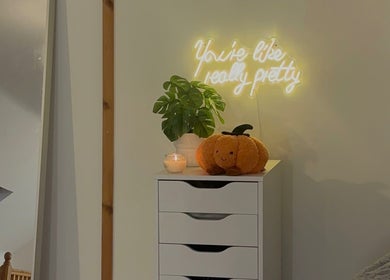 A cozy corner at Réalta Studio, County Mayo, with a glowing sign and plush decor on a white cabinet.