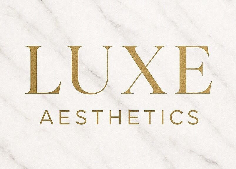 Luxe Aesthetics logo in gold on marble background, located in Lexington, Kentucky, US.