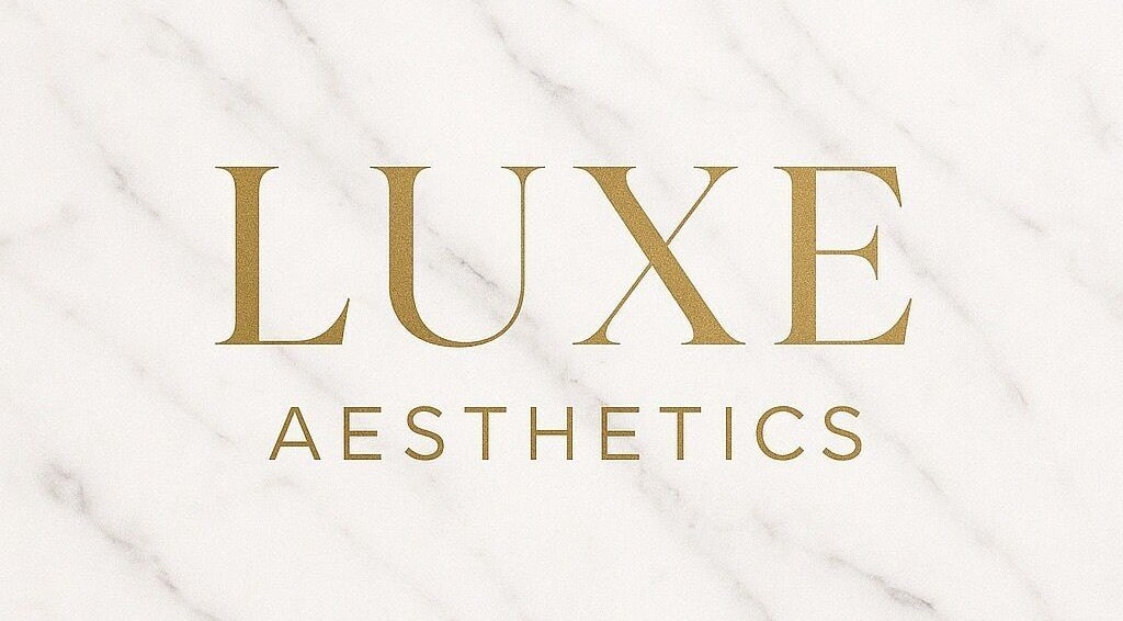 Luxe Aesthetics logo in gold on marble background, located in Lexington, Kentucky, US.