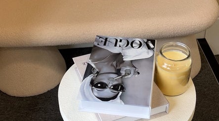 Cozy corner at braidsbyashlee, Birmingham, England, GB with fashion magazine and lit candle for relaxation.