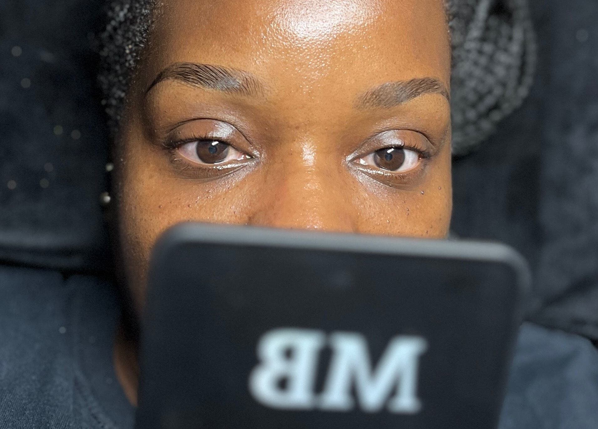 Client checking brows in mirror at Modestly Brow, Manchester, England, GB after treatment.