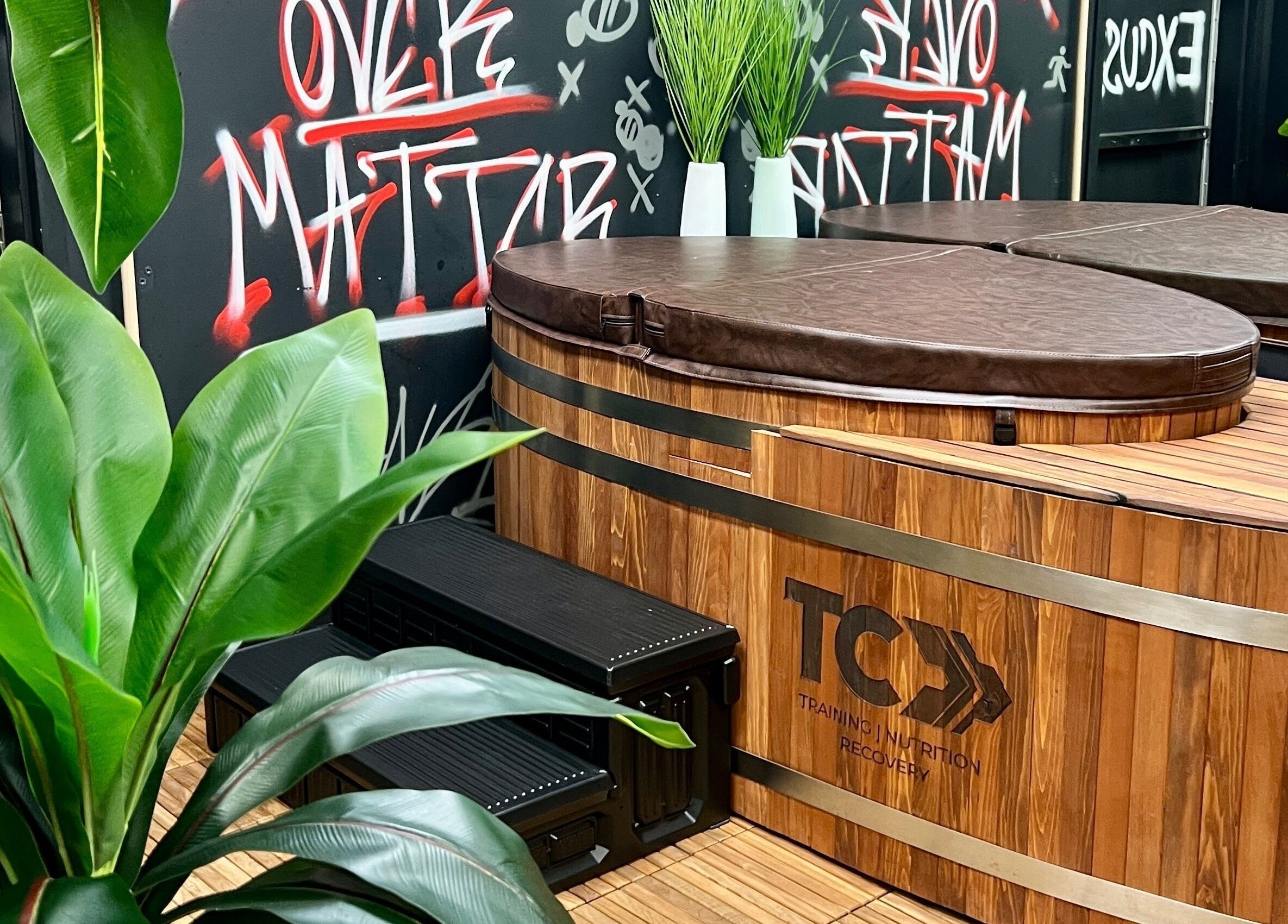 Luxurious wooden hot tub at Transformation Columbus, Powell, Ohio, US with vibrant plants and graffiti art.
