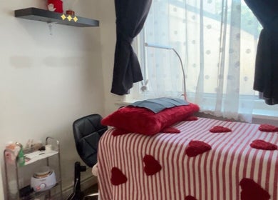 Cozy treatment room at Vibrae, London, England, GB with red accents and a striped blanket.