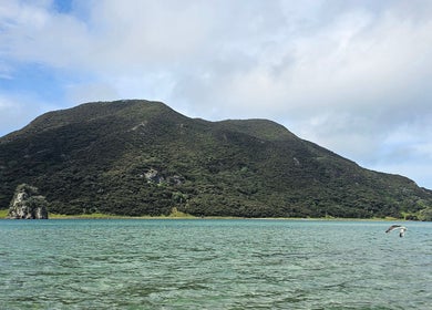 Serene lake view near Wai Ora Spa Therapies Tohoraha Clinic Pukenui, Northland Region, NZ with lush green hills.