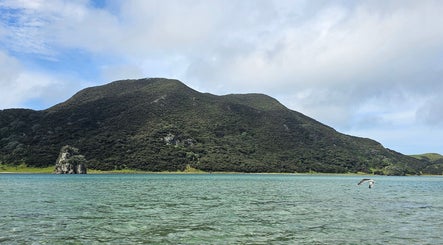 Serene lake view near Wai Ora Spa Therapies Tohoraha Clinic Pukenui, Northland Region, NZ with lush green hills.