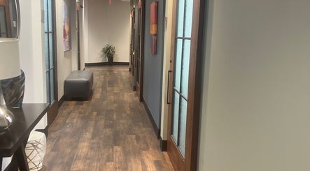 Elegant corridor at Thee Slay Babe, Sandy Springs, Georgia, US featuring wooden floors and soft lighting.