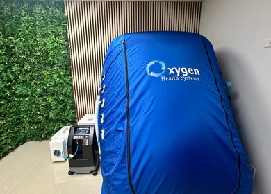 Oxygen therapy chamber at Hyperbaric Lounge LLC, Coral Springs, Florida, US with a lush greenery backdrop.