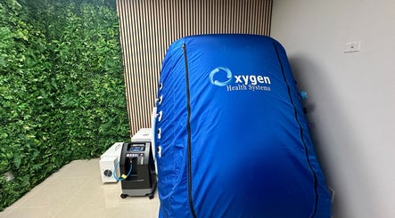 Oxygen therapy chamber at Hyperbaric Lounge LLC, Coral Springs, Florida, US with a lush greenery backdrop.