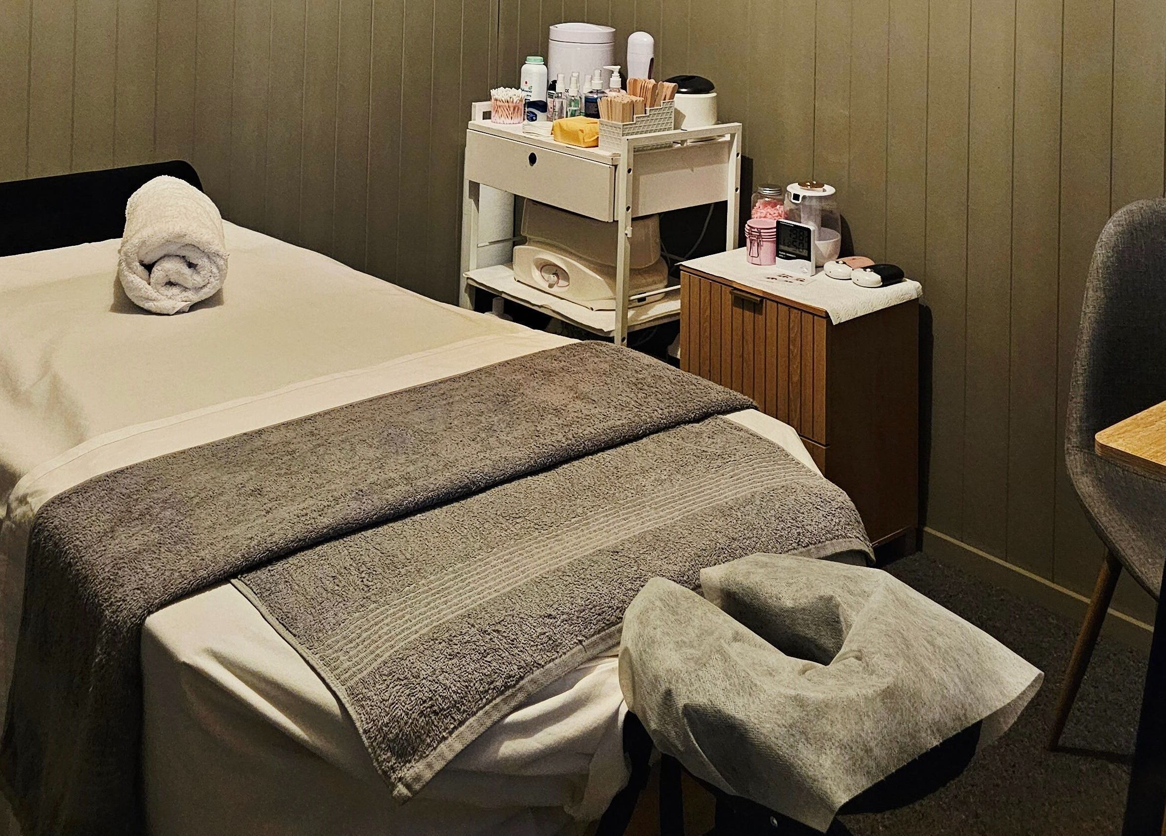 Relaxing treatment room at Elysian Beauty, Winton, Southland Region, NZ, featuring a massage table and cozy decor.