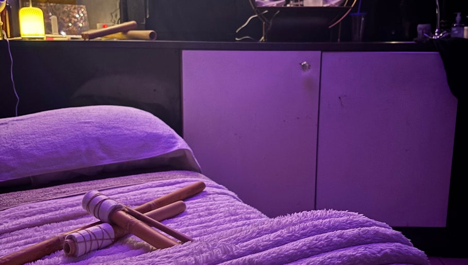 Relaxing massage setup at Sapphire Soul Alchemy, GB with bamboo sticks on a plush bed.