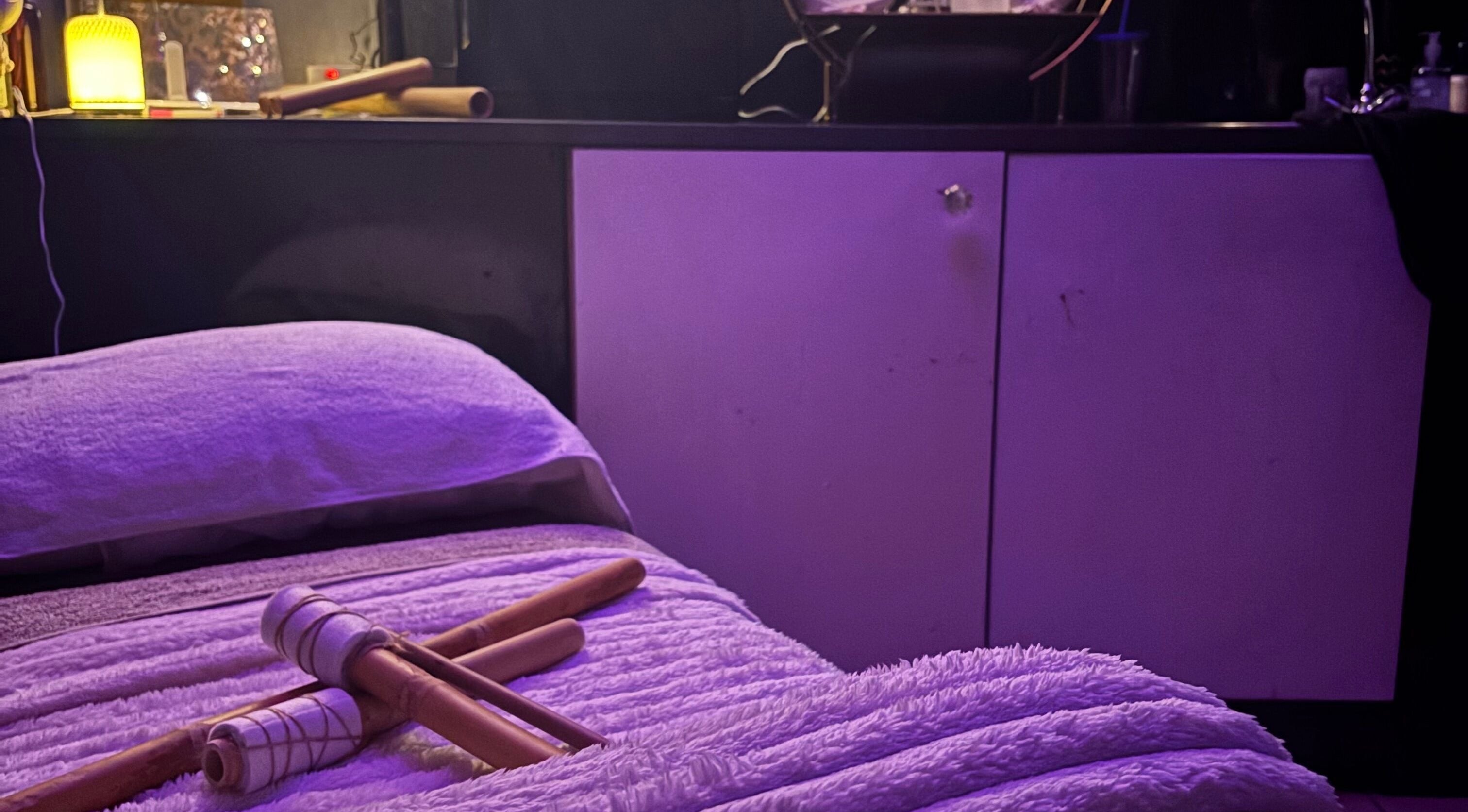 Relaxing massage setup at Sapphire Soul Alchemy, GB with bamboo sticks on a plush bed.