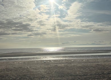 Tranquil seascape near Sapphire Soul Alchemy, GB, with sunlit waves and vast sky.