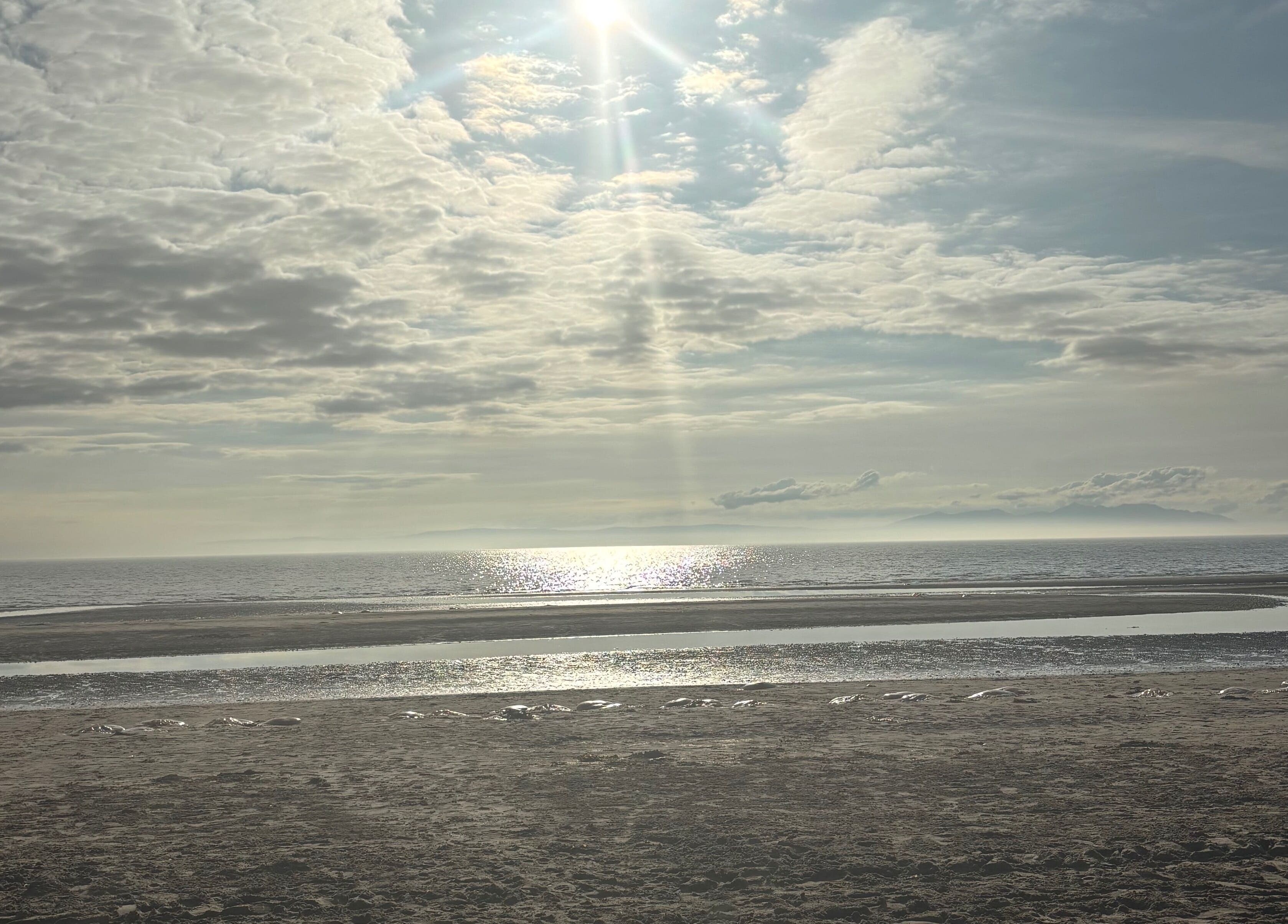 Tranquil seascape near Sapphire Soul Alchemy, GB, with sunlit waves and vast sky.