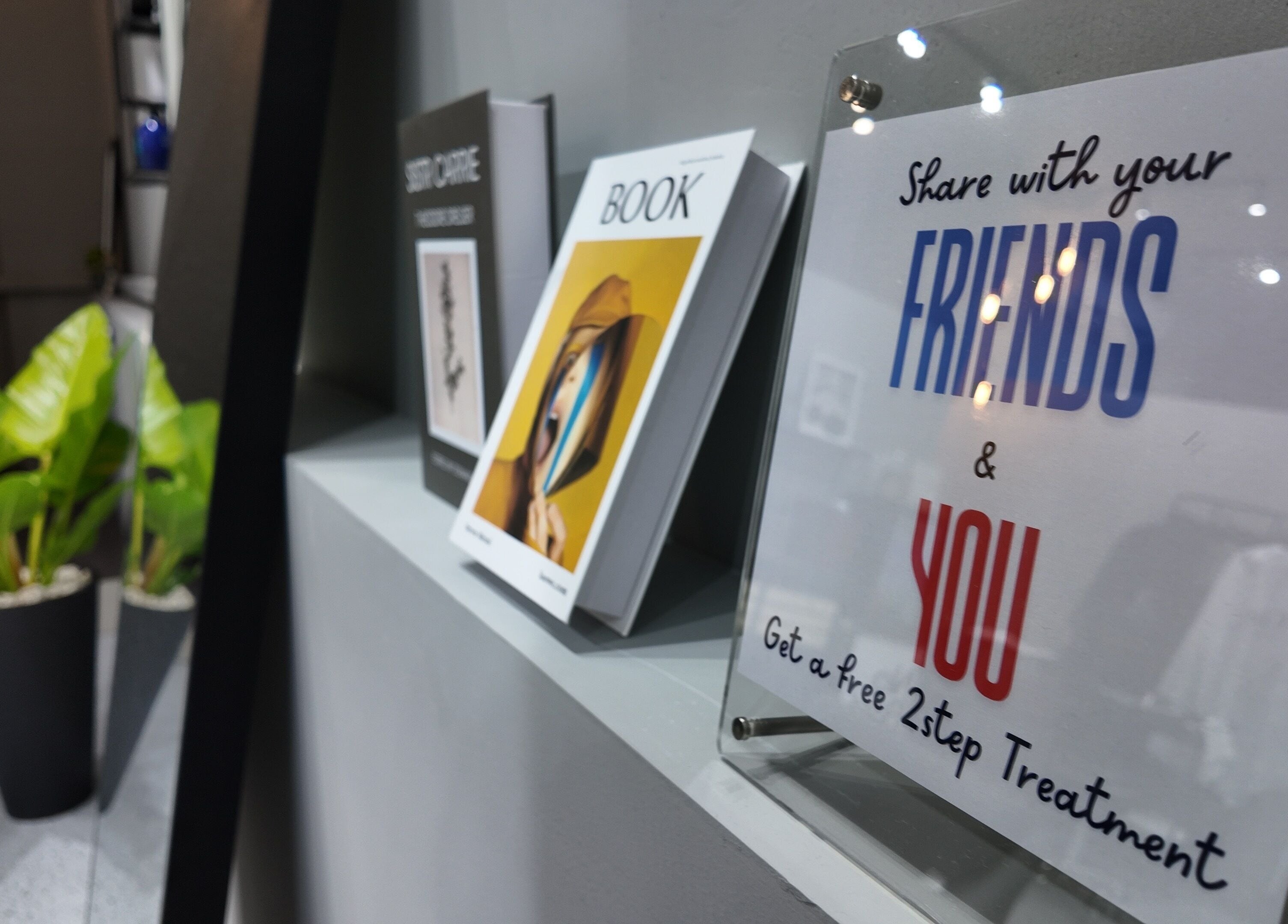 Modern display shelf at Ciel Japanese Hair Studio, Khlong Toei, Bangkok, TH showcasing stylish books and marketing sign.