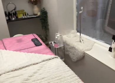 Cozy treatment room at Aisha Advanced Skincare, Burnley, England, GB, featuring a plush pink bed and gentle lighting.