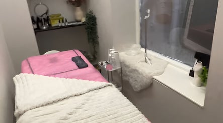 Cozy treatment room at Aisha Advanced Skincare, Burnley, England, GB, featuring a plush pink bed and gentle lighting.
