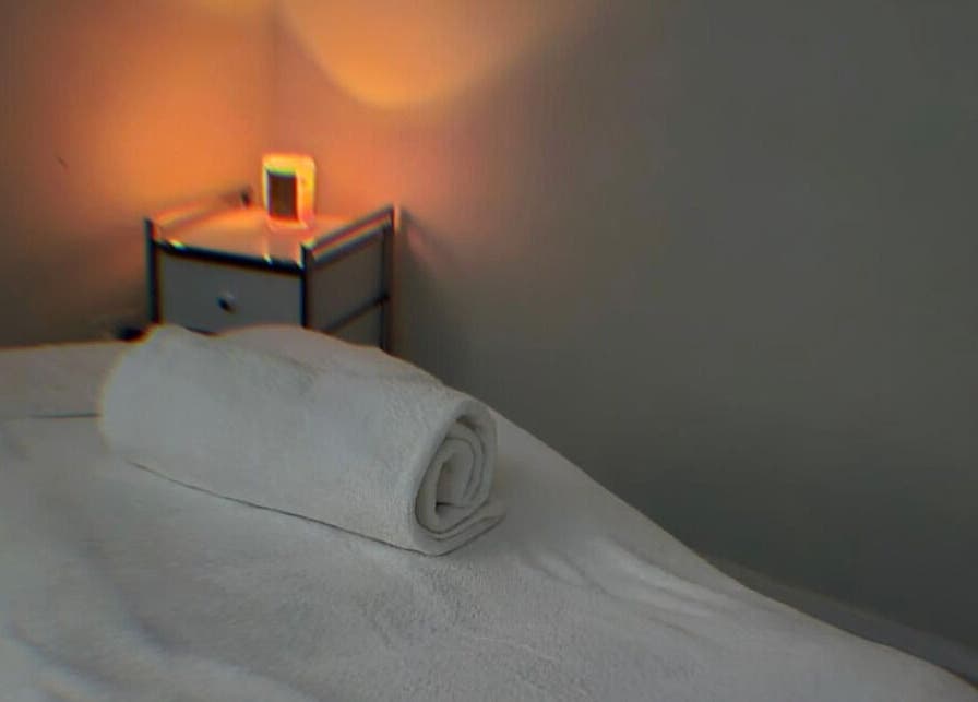 Cozy massage room at Bare Bronze Skin Clinic, Strathdale, Victoria, AU with soft lighting and a rolled towel.