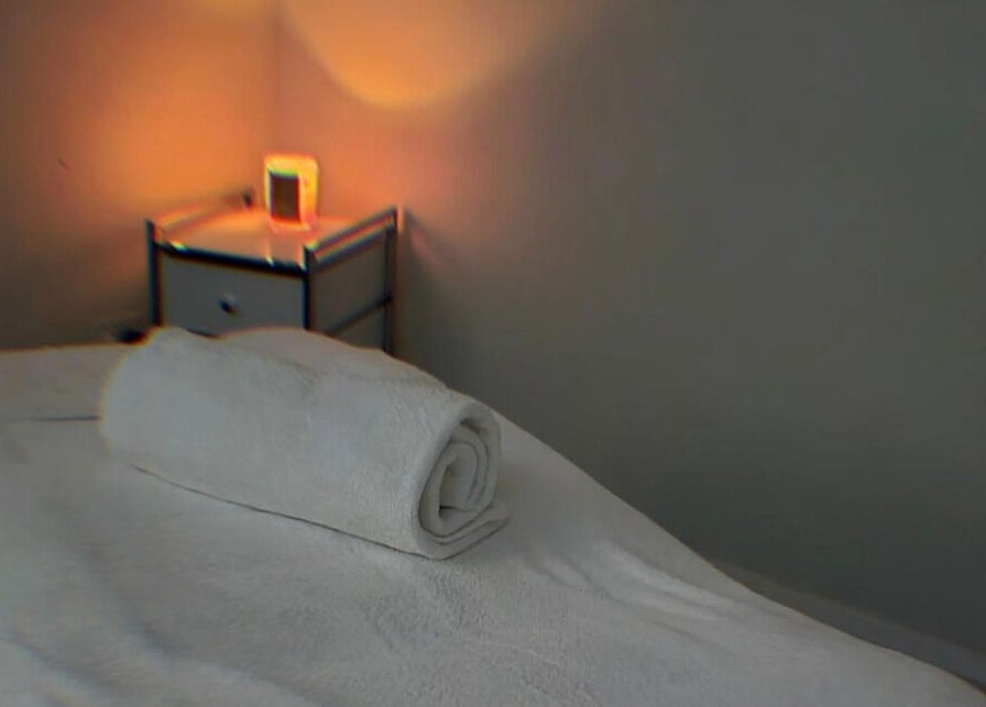 Cozy massage room at Bare Bronze Skin Clinic, Strathdale, Victoria, AU with soft lighting and a rolled towel.