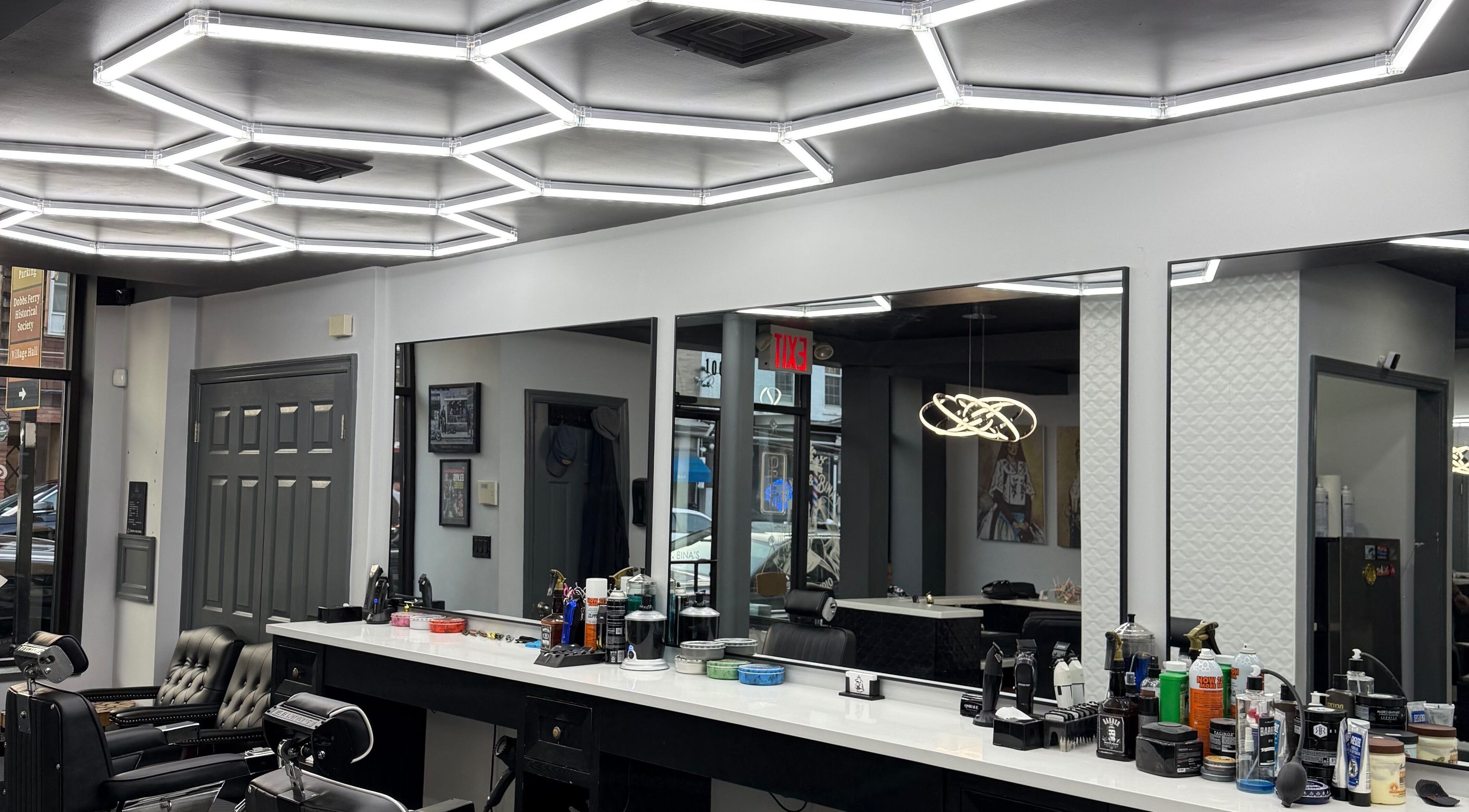 Modern interior of Benny & Bina’s salon, Dobbs Ferry, New York, US with sleek barber chairs and bright lighting.
