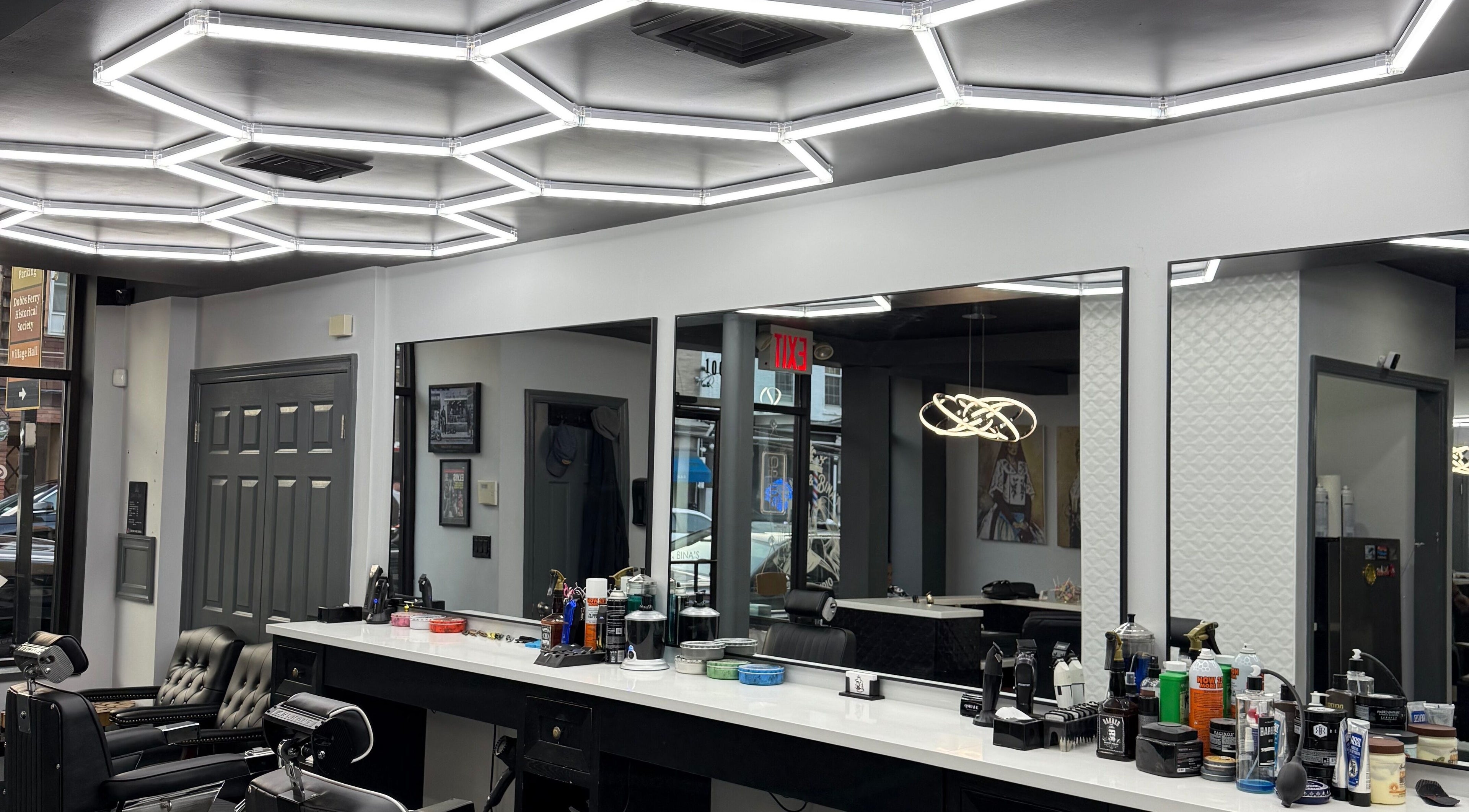 Modern interior of Benny & Bina’s salon, Dobbs Ferry, New York, US with sleek barber chairs and bright lighting.
