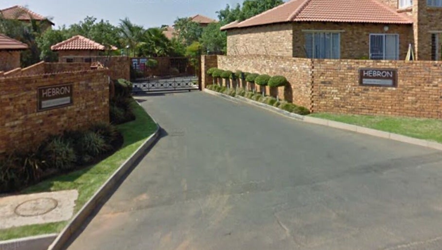 Entrance view of Rocky Pinnacle, Randburg, Gauteng, ZA, with brick walls and lush greenery.