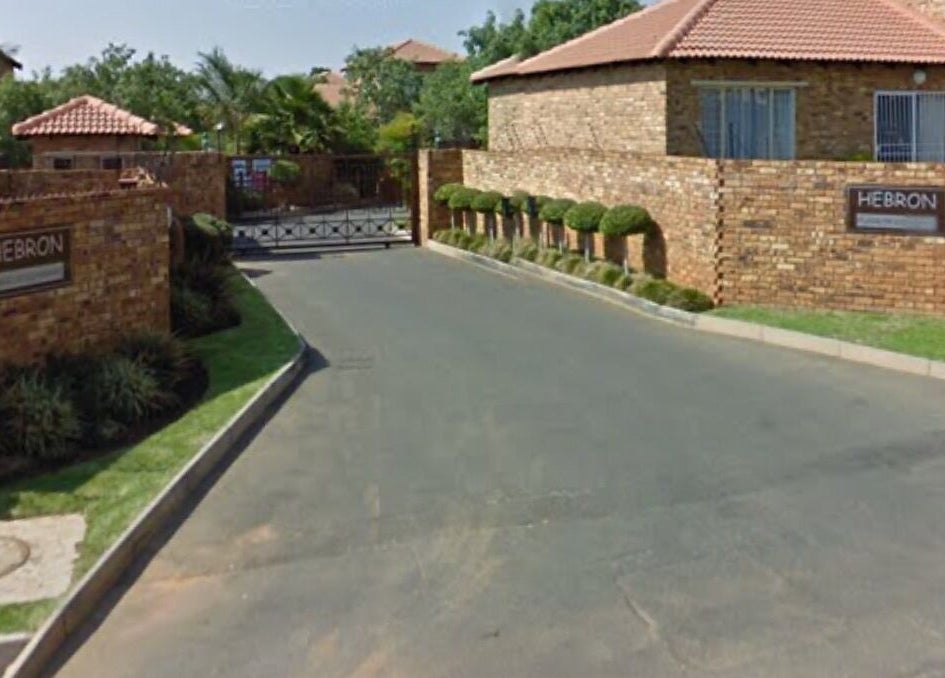 Entrance view of Rocky Pinnacle, Randburg, Gauteng, ZA, with brick walls and lush greenery.