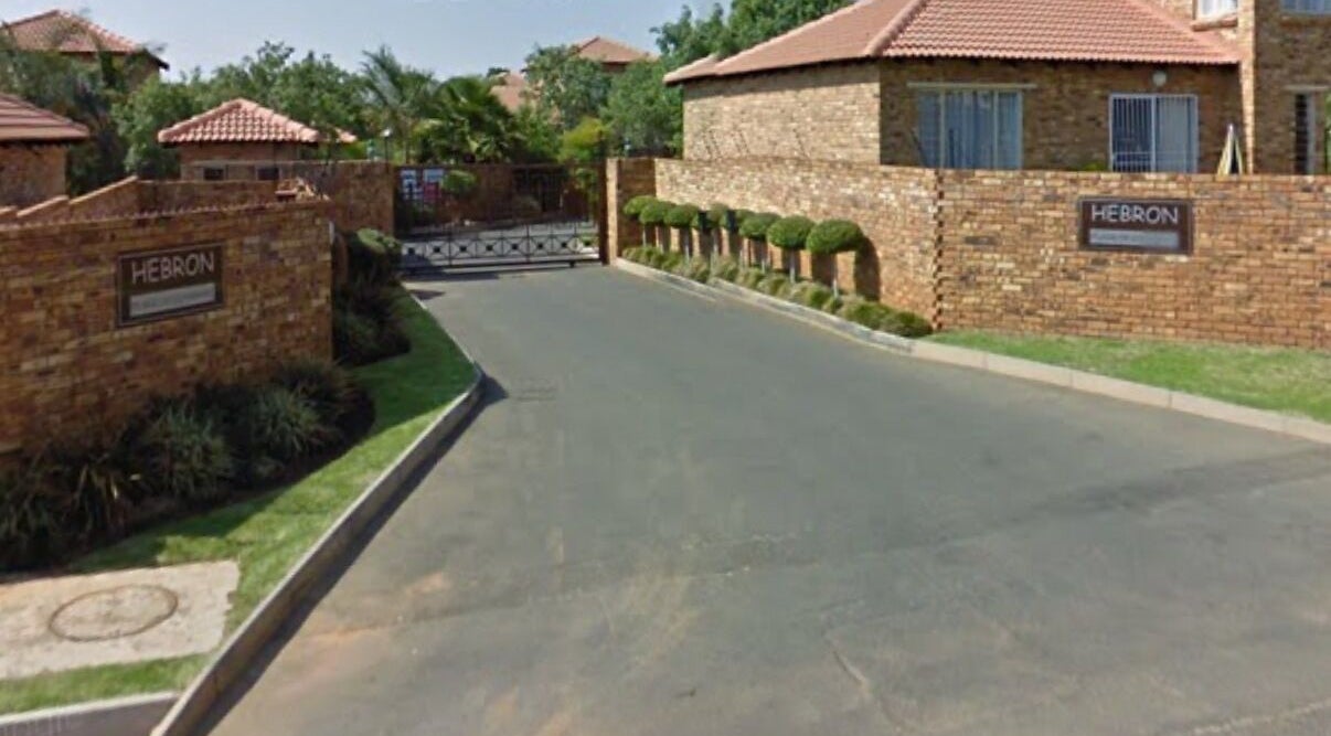 Entrance view of Rocky Pinnacle, Randburg, Gauteng, ZA, with brick walls and lush greenery.