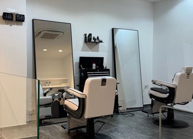 Interno moderno di George The Barber a Crema, Lombardia, IT con poltrone eleganti e specchi ampi.
