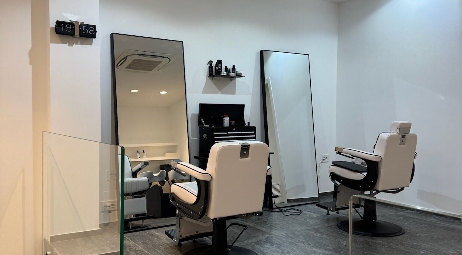 Interni moderni di George The Barber a Crema, Lombardia, IT con poltrone bianche e specchi eleganti.