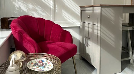 Elegant red velvet chair and side table at Sims Beauty, Stilton, England, GB. Perfect for relaxation.