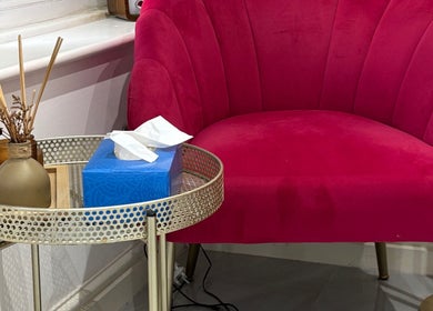 Plush red chair with side table in Sims Beauty, Stilton, England, GB, offering comfort and style.