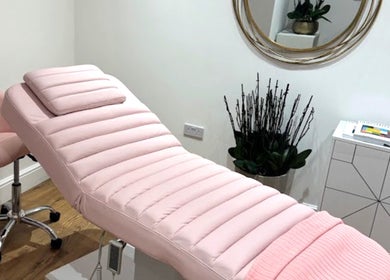 Relaxing treatment room at Micro Glow PMU, London, England, GB with a pink massage bed and elegant decor.
