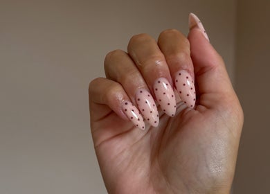 Moda nail art in Edinburgh features chic polka dot design on a hand with glossy manicure.