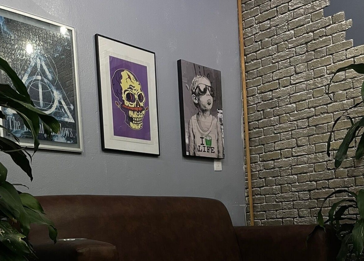 Decoración moderna en Barbería Men's Cave, El Pueblito, Querétaro, MX, con arte en la pared y plantas verdes.